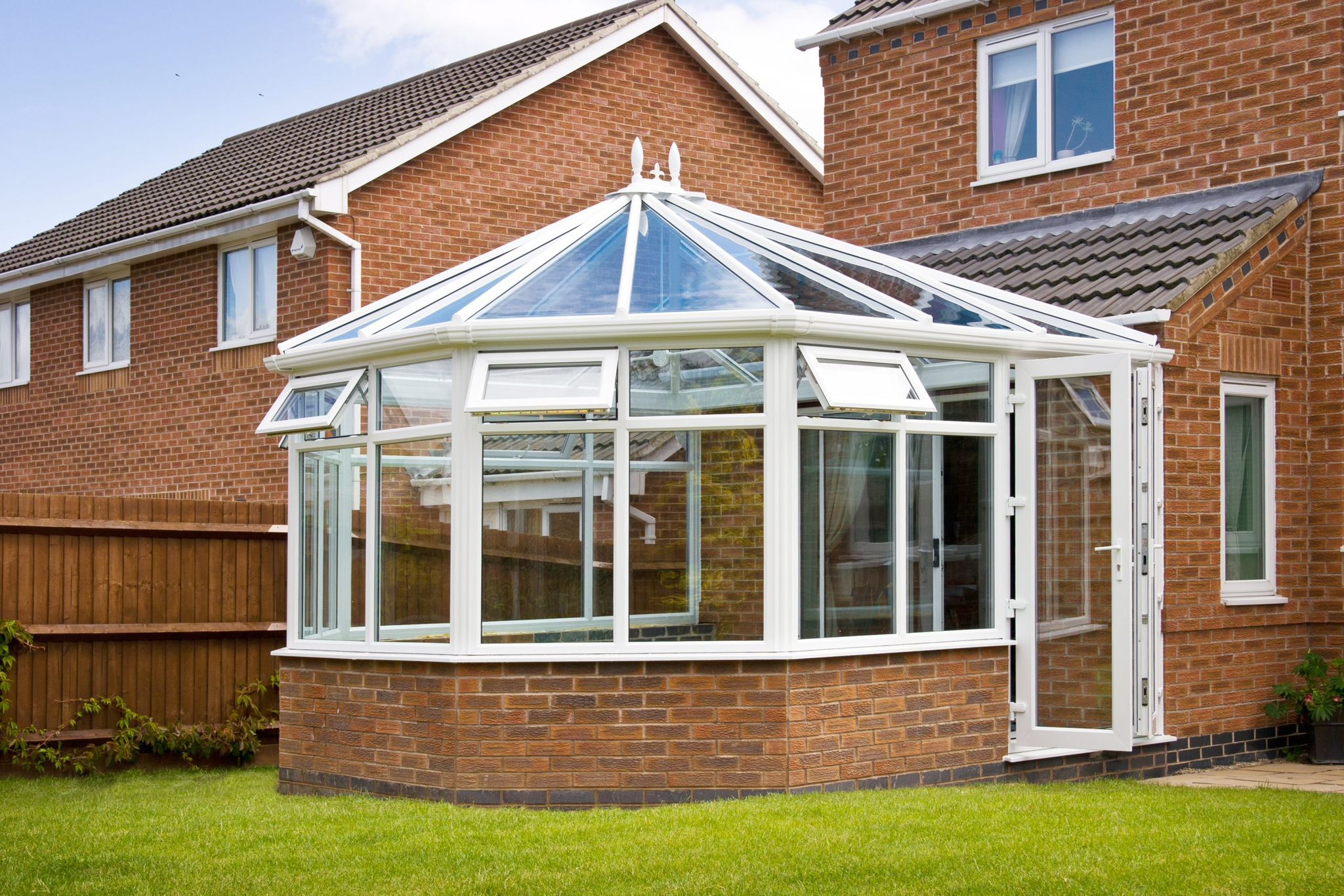 White conservatory extension with open doors and brick base
