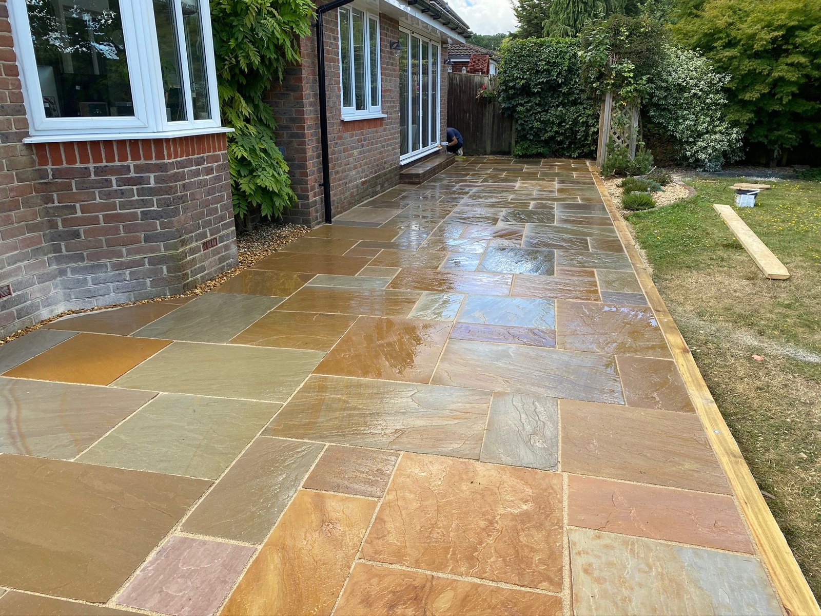 Natural stone patio installed along the side of a house